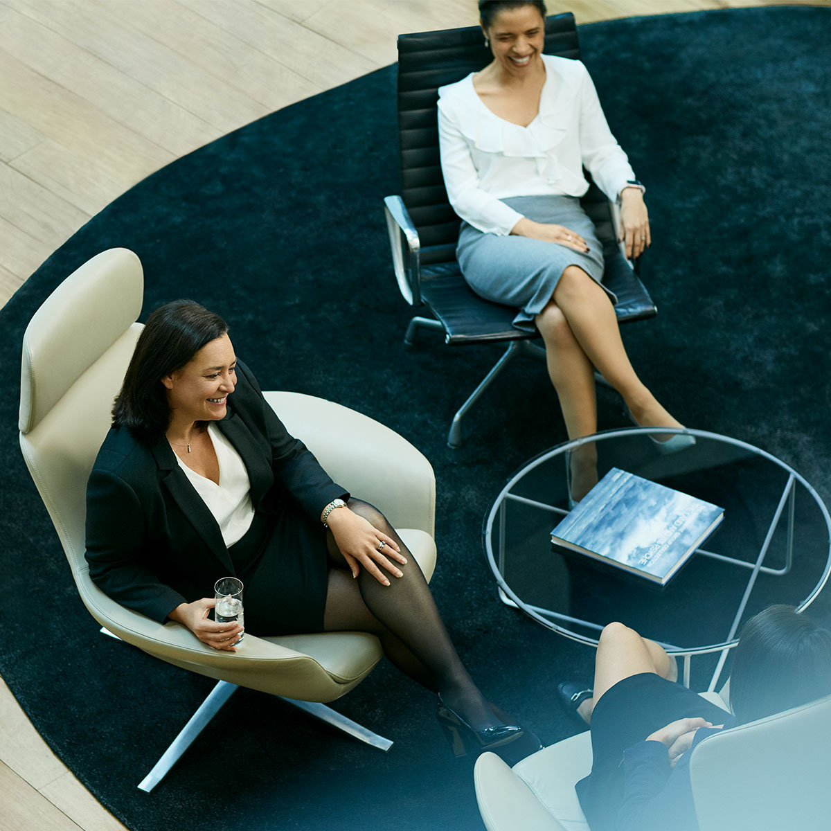 A birds eye shot of 3 business woman sitting at a small black round coffee table. Macquarie - Sherise Bianca