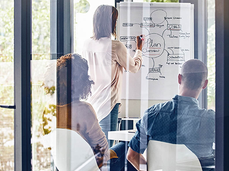 People in meeting room chatting over flip chart plan