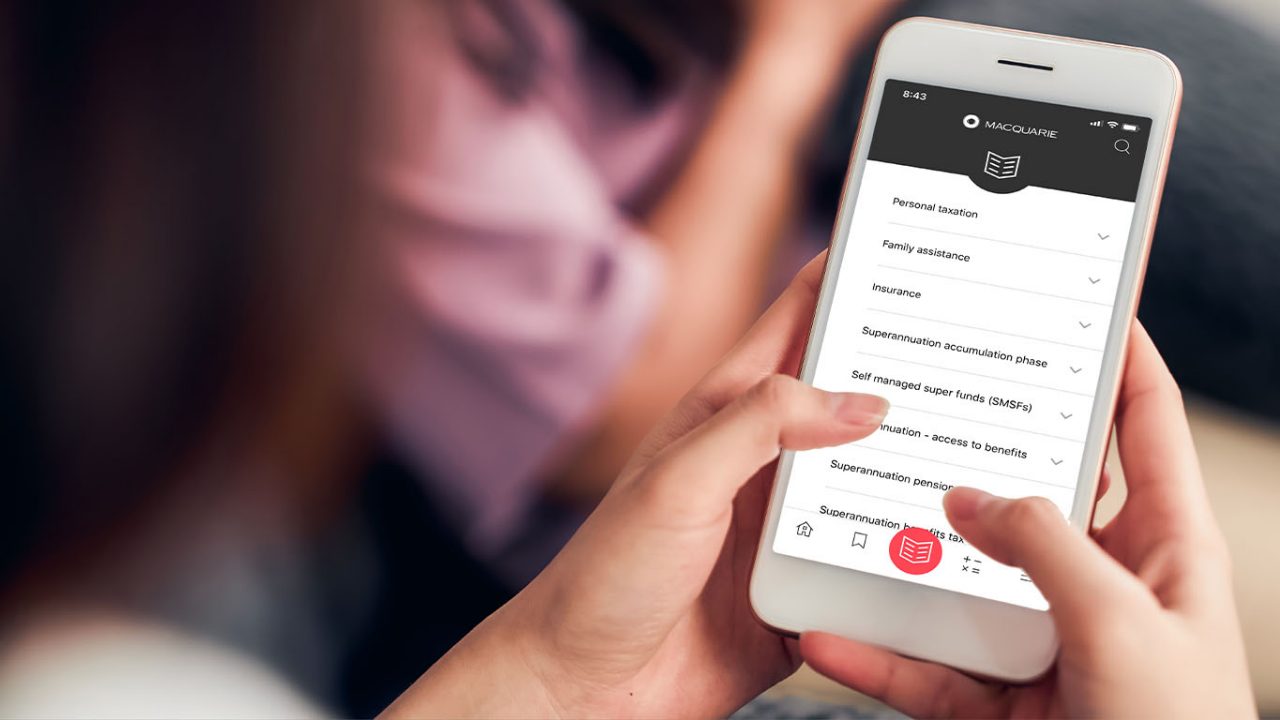 A hand holding a phone with the Macquarie Little Black Book open on the screen.