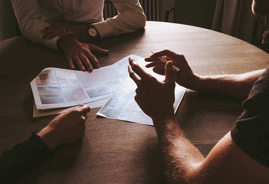 Meeting with three people, discussing over documents on table.