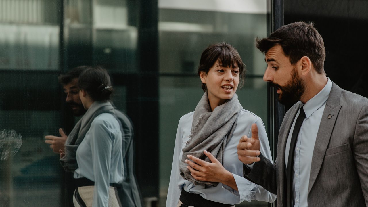 Two young coworkers walking and talking