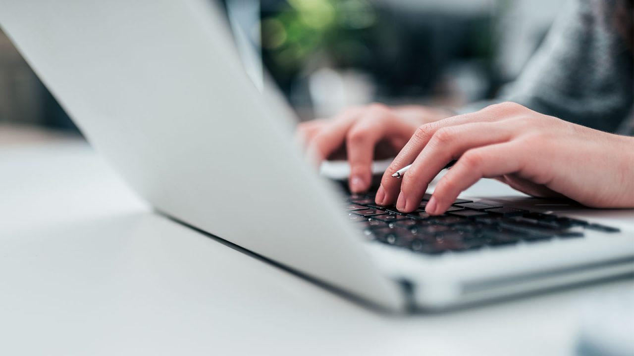 Close up shot of a person’s hands typing on laptop.