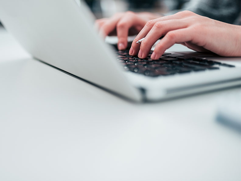 Close up shot of a person’s hands typing on laptop.