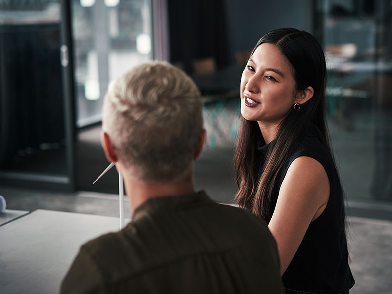 Two businesswomen sitting and talking to each other while in their office during the day