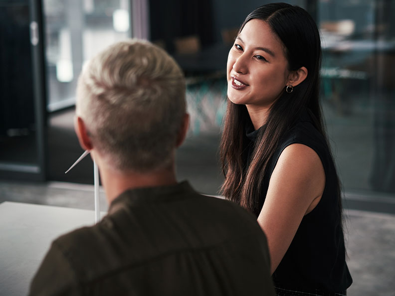 Two businesswomen sitting and talking to each other while in their office during the day