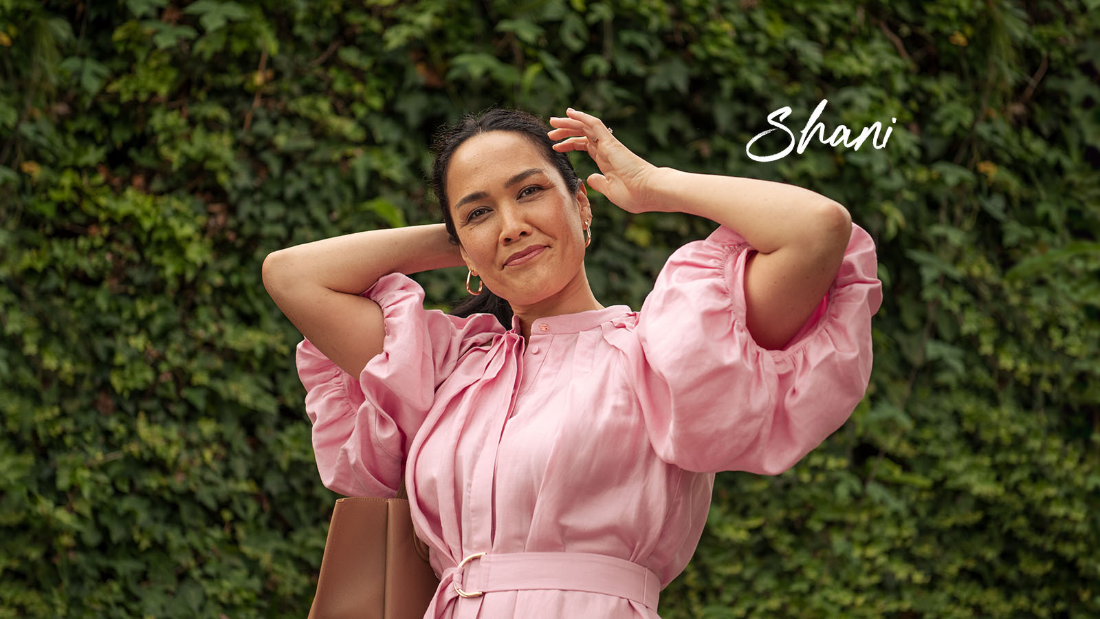 Shani smiling in front of greenery