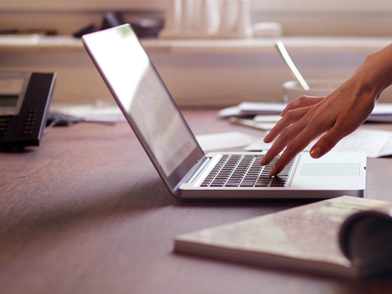 Arm reaching to laptop sitting on desk