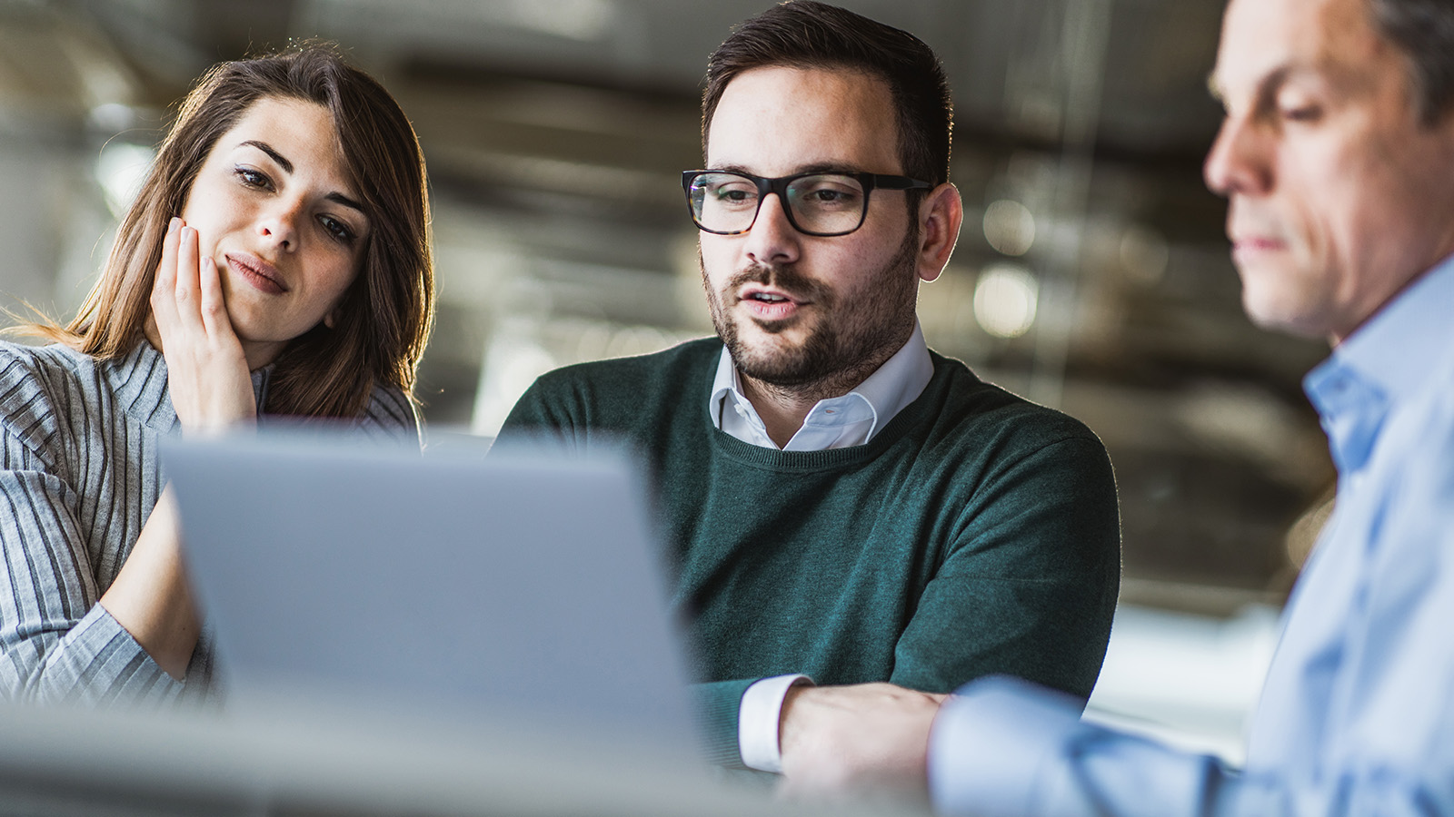 Three office workers looking at laptop screen