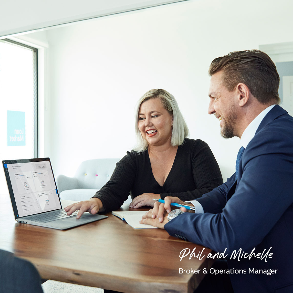 Phil and Michelle brokers sitting in office on laptop together smiling