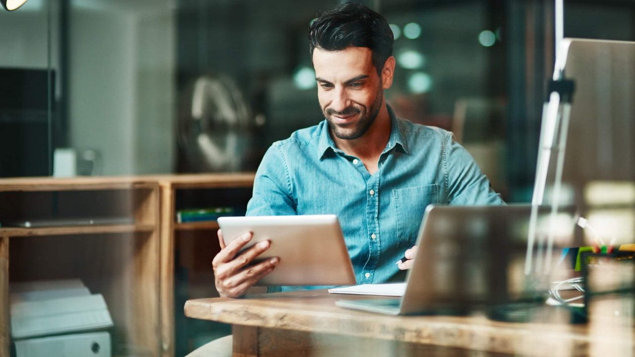 Professional man using tablet in front of laptop
