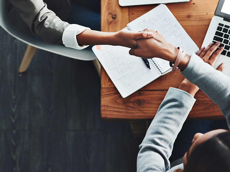 Handshake at table with laptop in frame