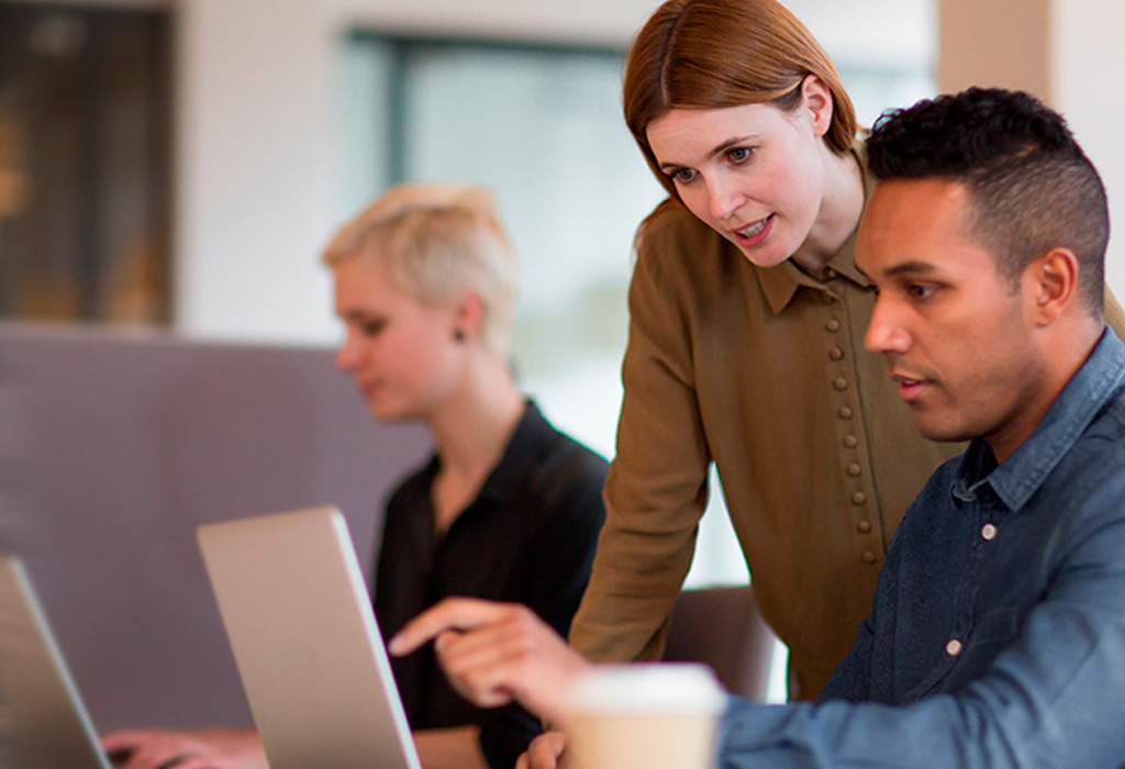 Two colleagues helping each other looking over laptop