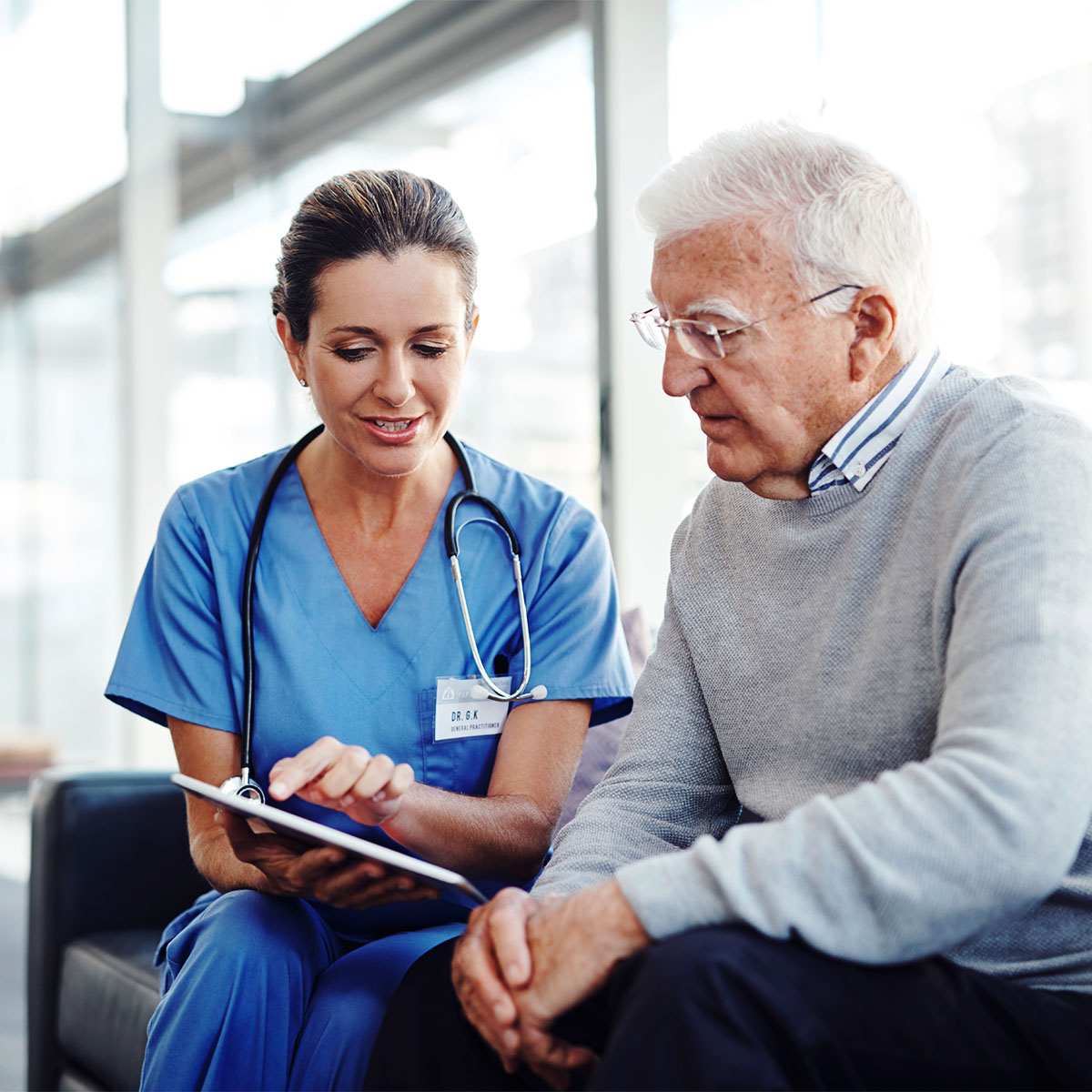 Female medical professional showing her elderly patient something on a digital tablet