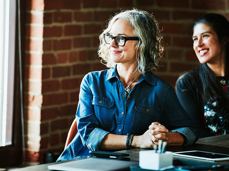 Mature smiling businesswoman leading meeting with colleagues and clients in office conference 