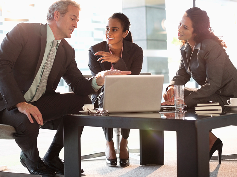 Three business people discussing over information on laptop in office environment