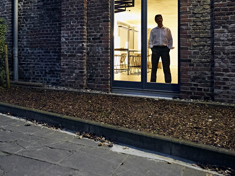 Businessman standing in window of building at night