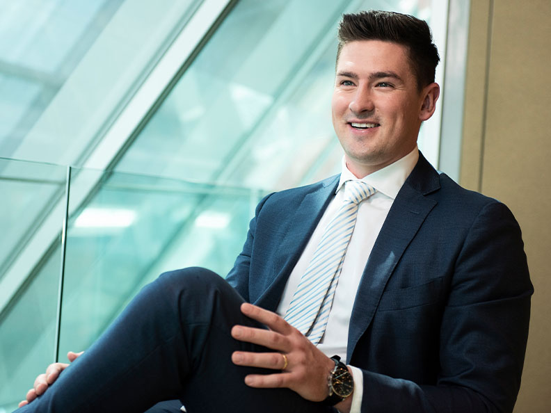 A young businessman dressed professional smiling and sitting in an open meeting room