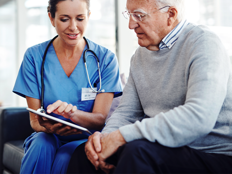 Female medical professional showing elderly patient tablet