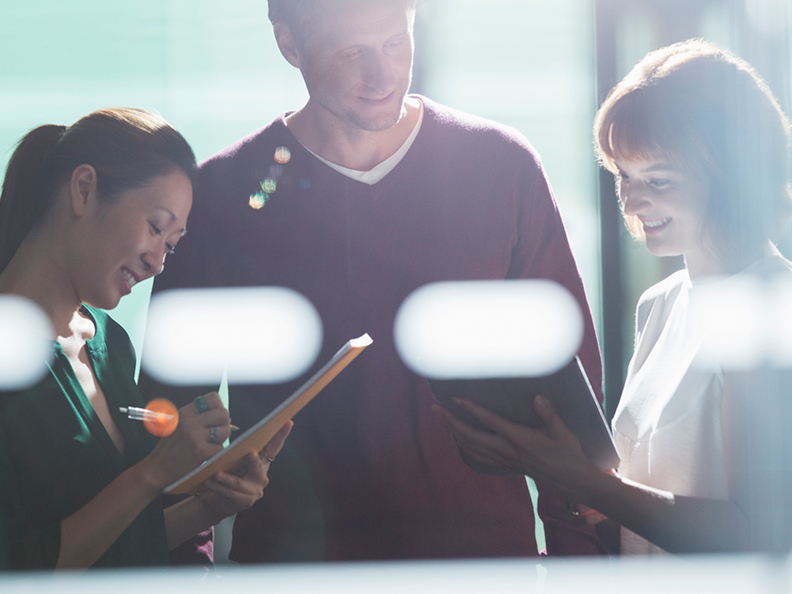 Three business people casually discussing with lens flare