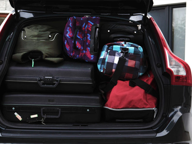 lots of luggages in a black car trunk