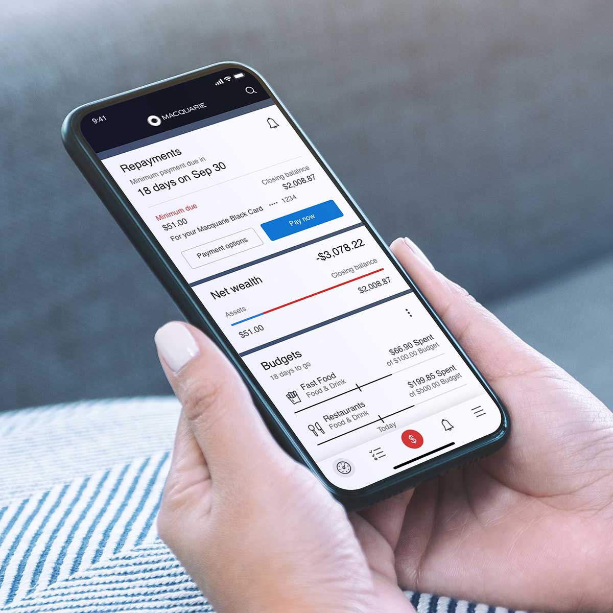 Two hands holding onto a phone with the Macquarie app opened to a detailed dashboard screen