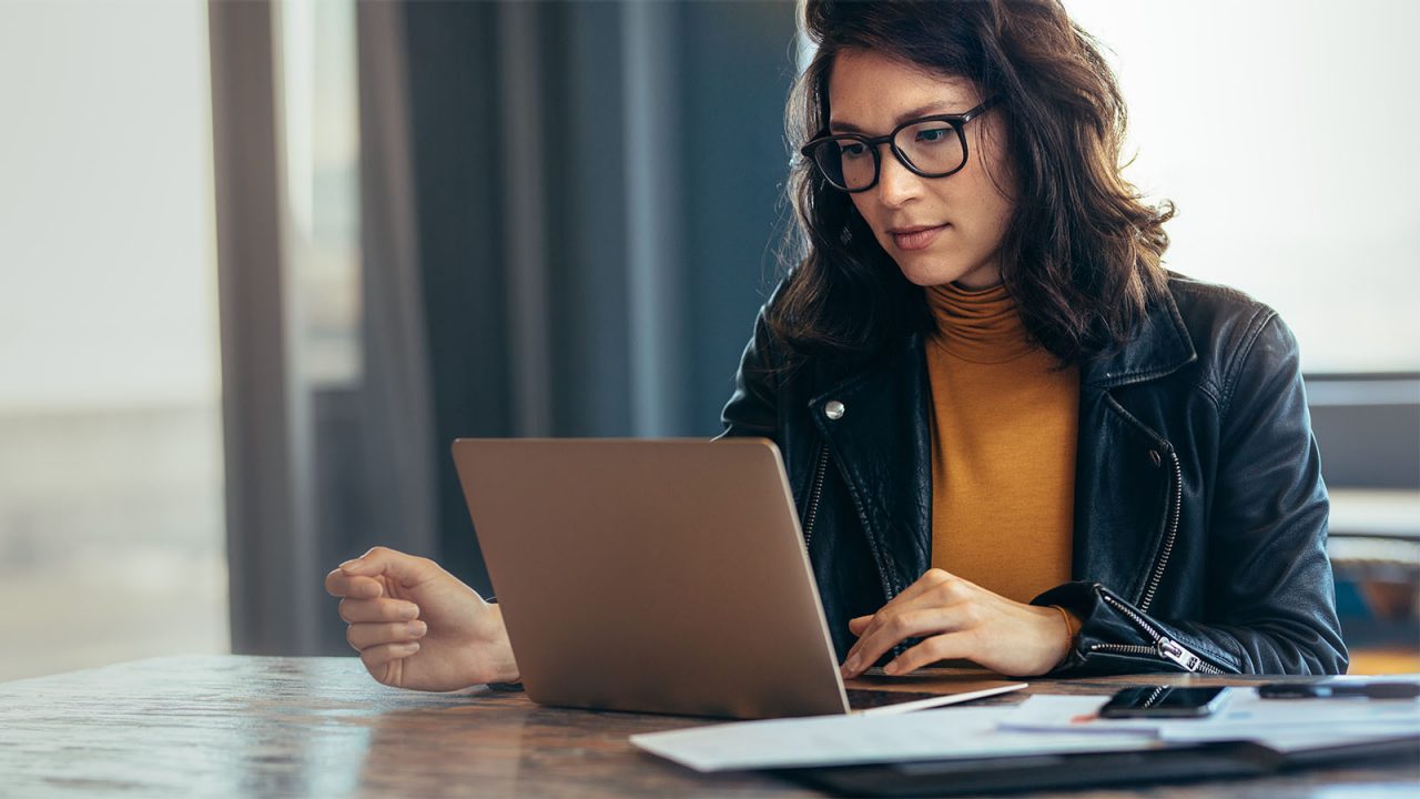 Business woman busy working on laptop computer in open office.