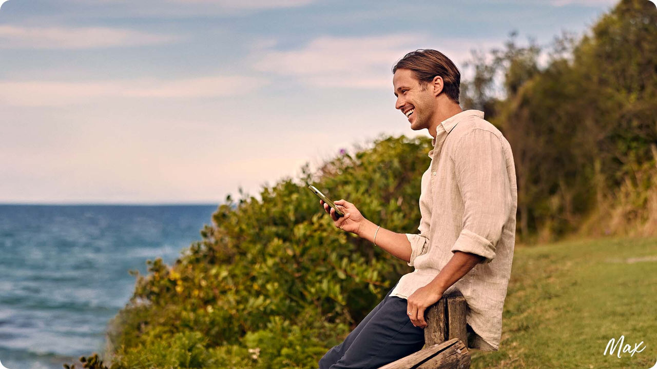 Max holding phone and smiling