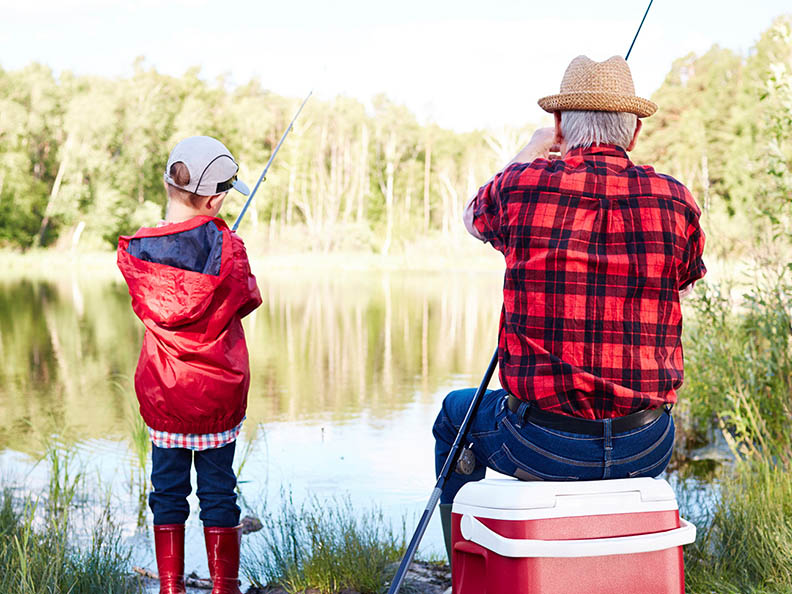Grandfather and grandson fishing on a lake.