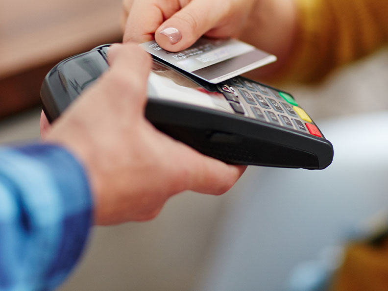 Close-up of unrecognisable customer choosing contactless payment using credit card while wait staff accepts payment over nfc tap pay pass technology