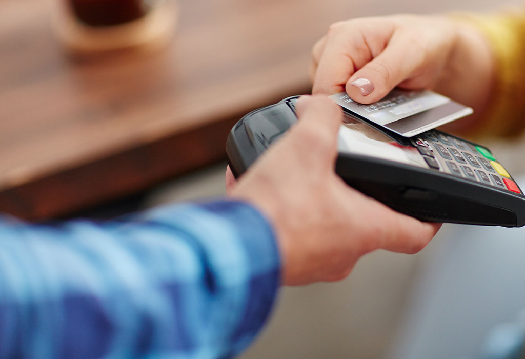 Close-up of unrecognisable customer choosing contactless payment using credit card while wait staff accepts payment over nfc tap pay pass technology