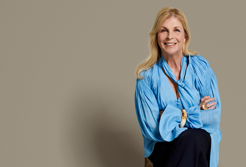 Lianne sitting in a studio and smiling at the camera with her arms crossed