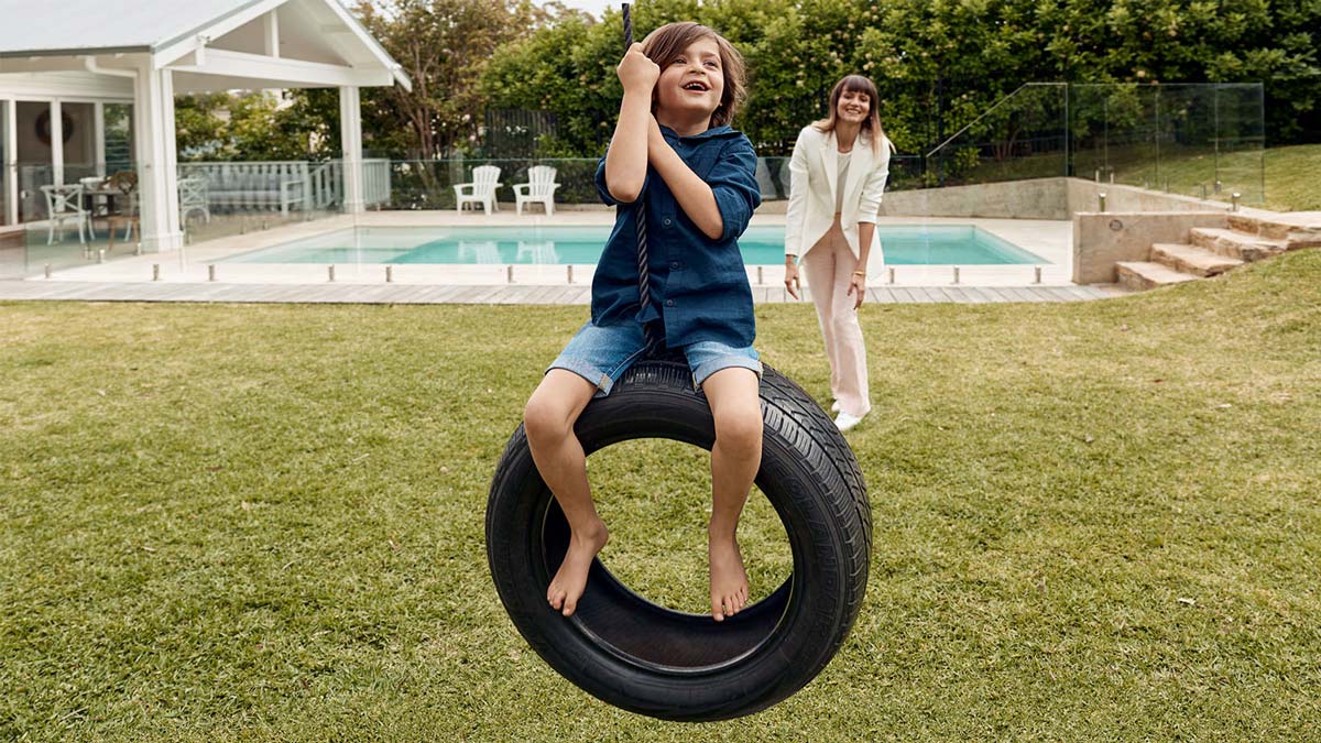 Young boy sits on a tyre wing as his aunt pushes him