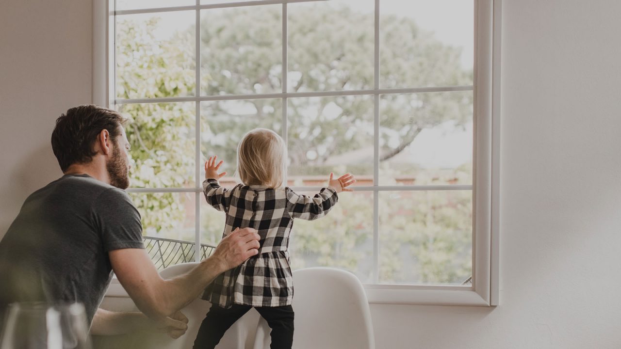 father and child looking out window
