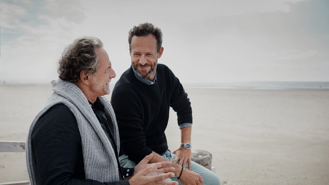 elder father and son talking at the beach