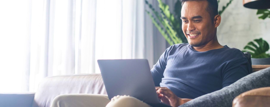 Image of a man sitting and smiling at a laptop