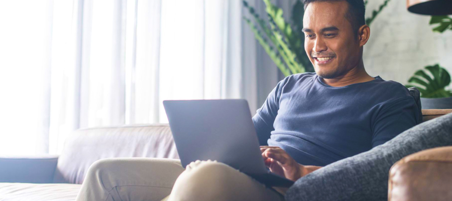 Image of a man sitting and smiling at a laptop