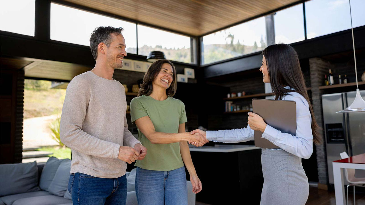 Business woman shaking hands with couple in home