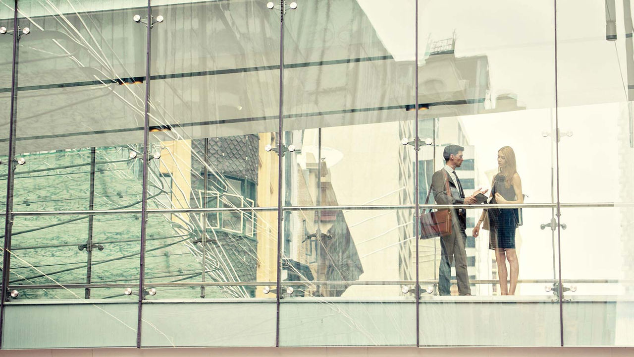 Business man and woman talking in glass office
