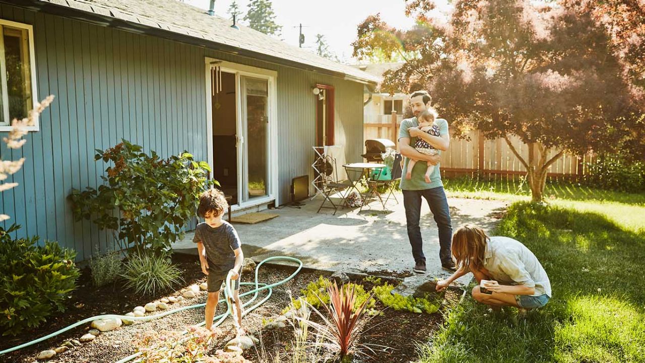 Family watering garden in backyard on summer morning