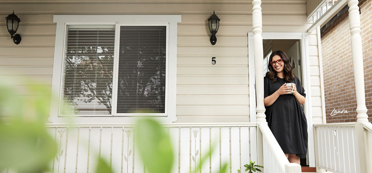 Laura standing on veranda with a cup