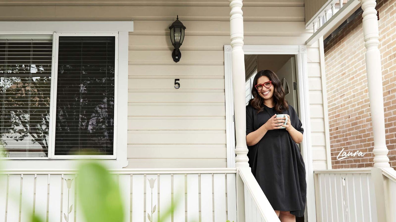 Laura standing on veranda with a cup