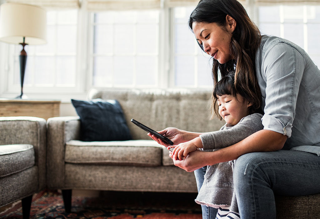 Mother sitting in lounge with daughter using phone.