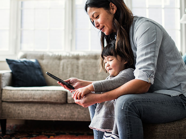 Mother sitting in lounge with daughter using phone.