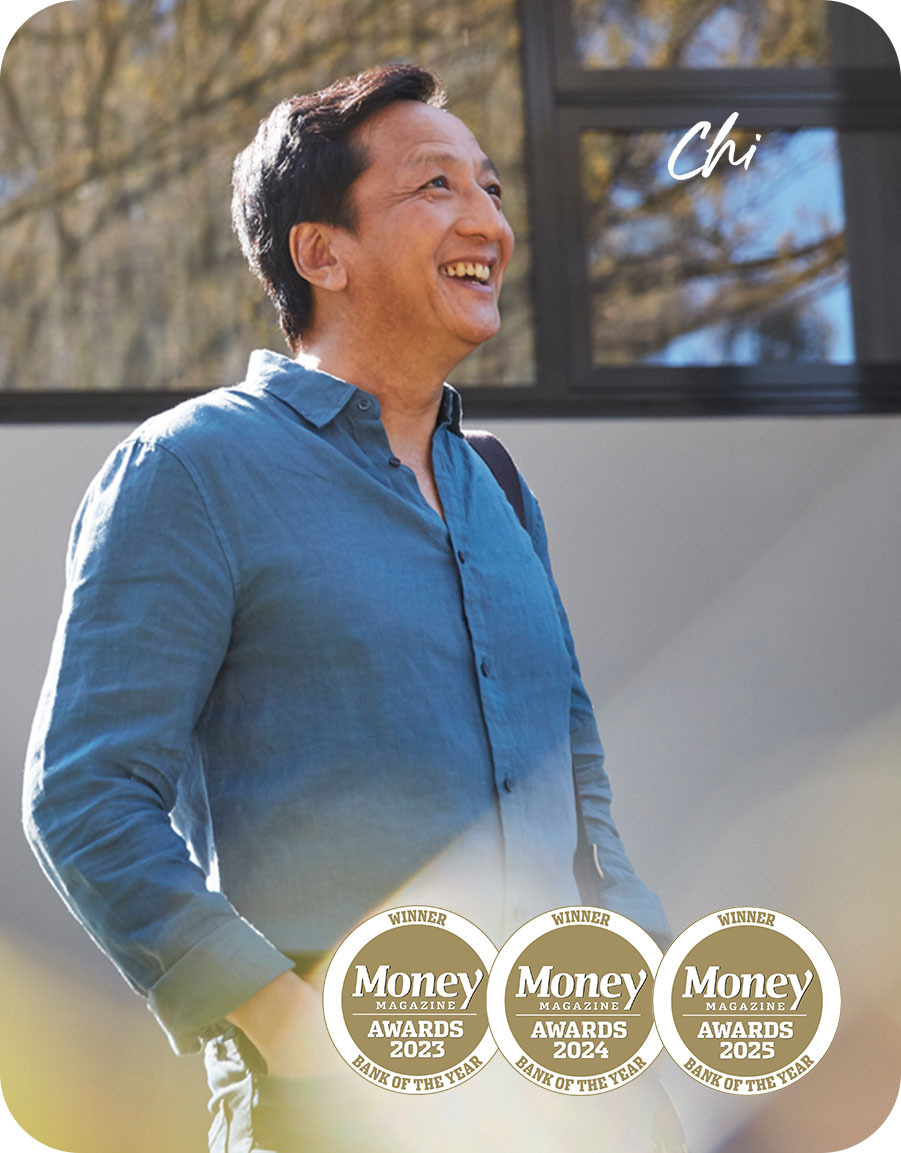 Chi, home loan customer, with blue shirt and bag standing outside his home in the sunshine and smiling