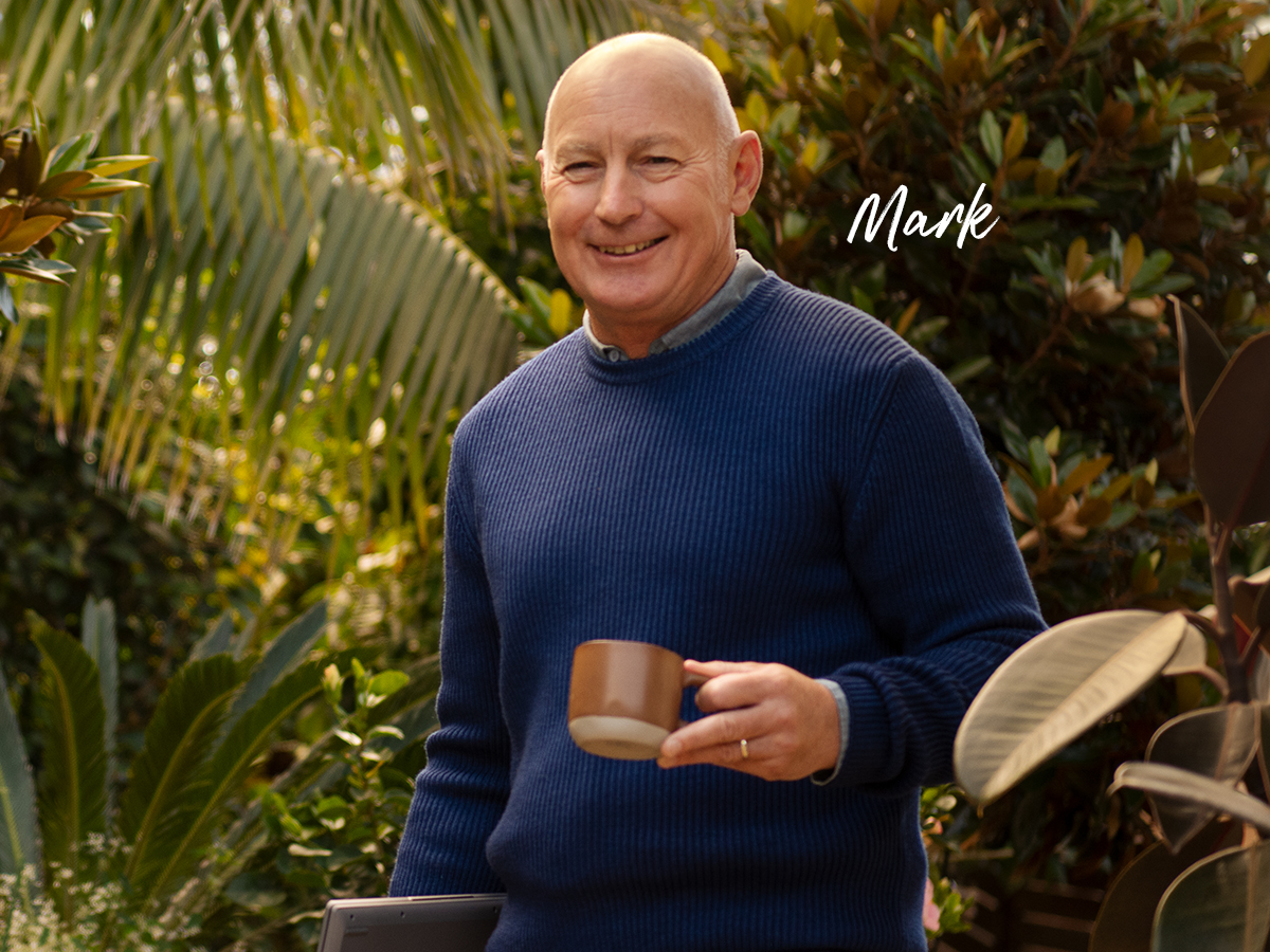 Mark a home loan customer smiling and holding mug in front of greenery outside
