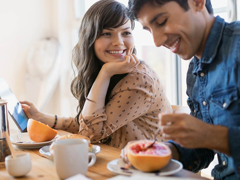 Smiling couple at kitchen table with ipad