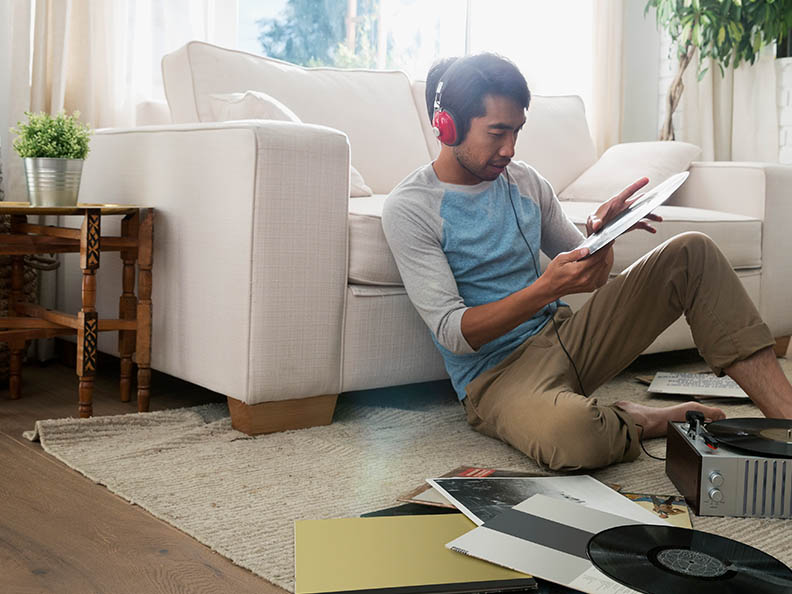 Man with headphones listening vinyl records living room