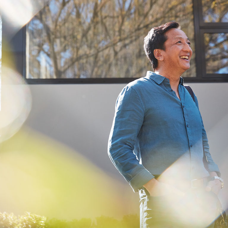 Middle aged Asian man standing outside his home on a sunny day. Macquarie customer - Chi