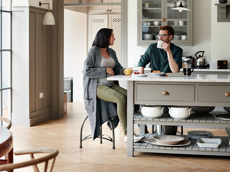 A young couple having breakfast together at home in their kitchen, the woman is pregnant