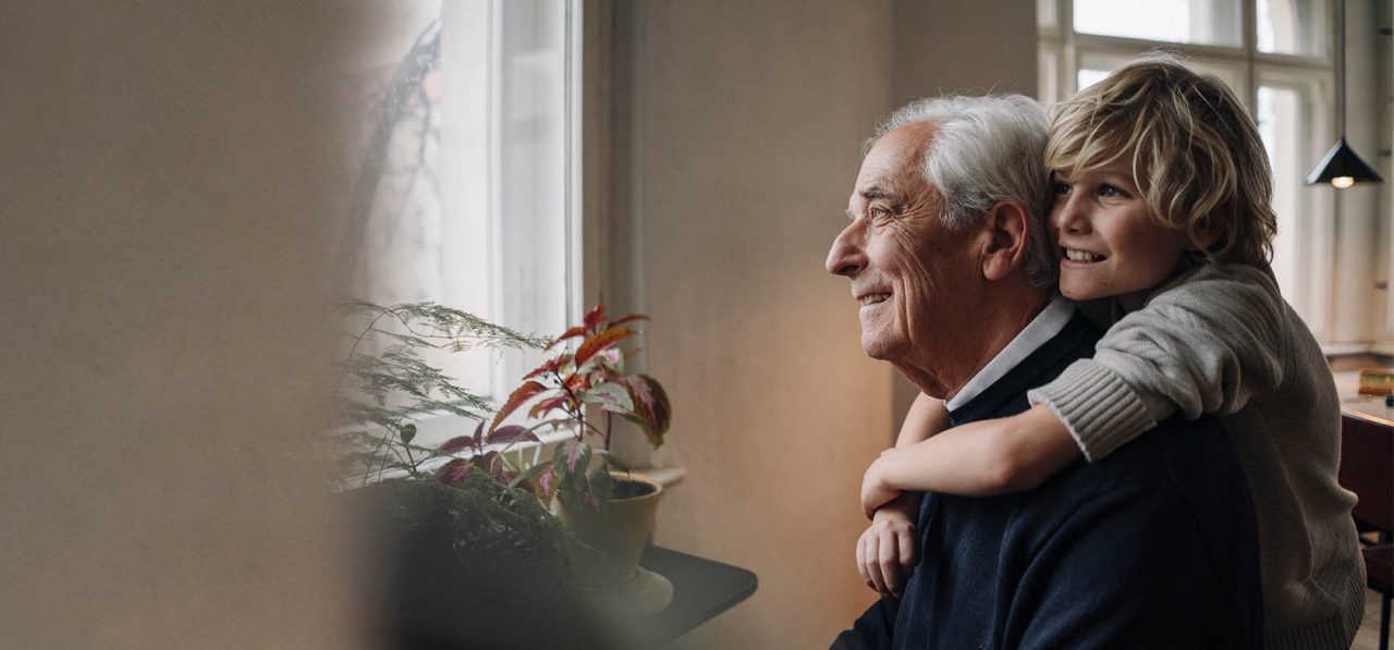 Happy grandson embracing grandfather at home